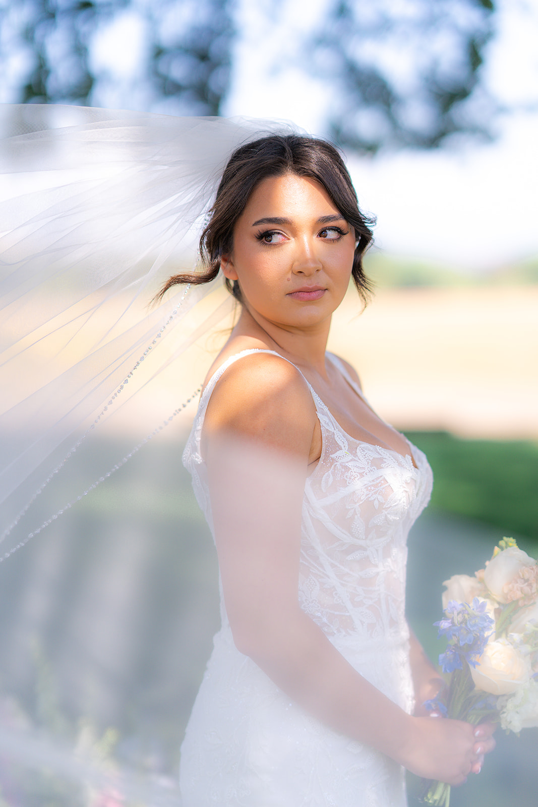 Bride wearing a wedding veil beneath an oak tree at Rainbow Oaks Ranch in Sanger, California.