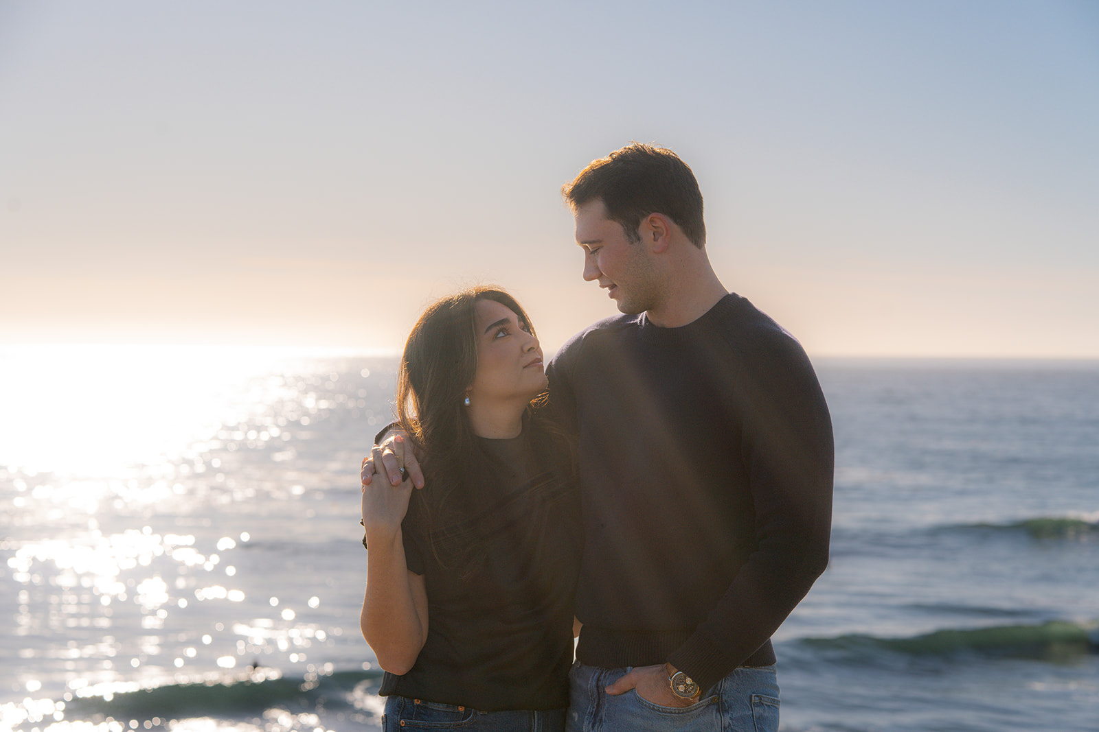 Couple on a scenic Santa Cruz cliffside overlooking the ocean at sunset.
