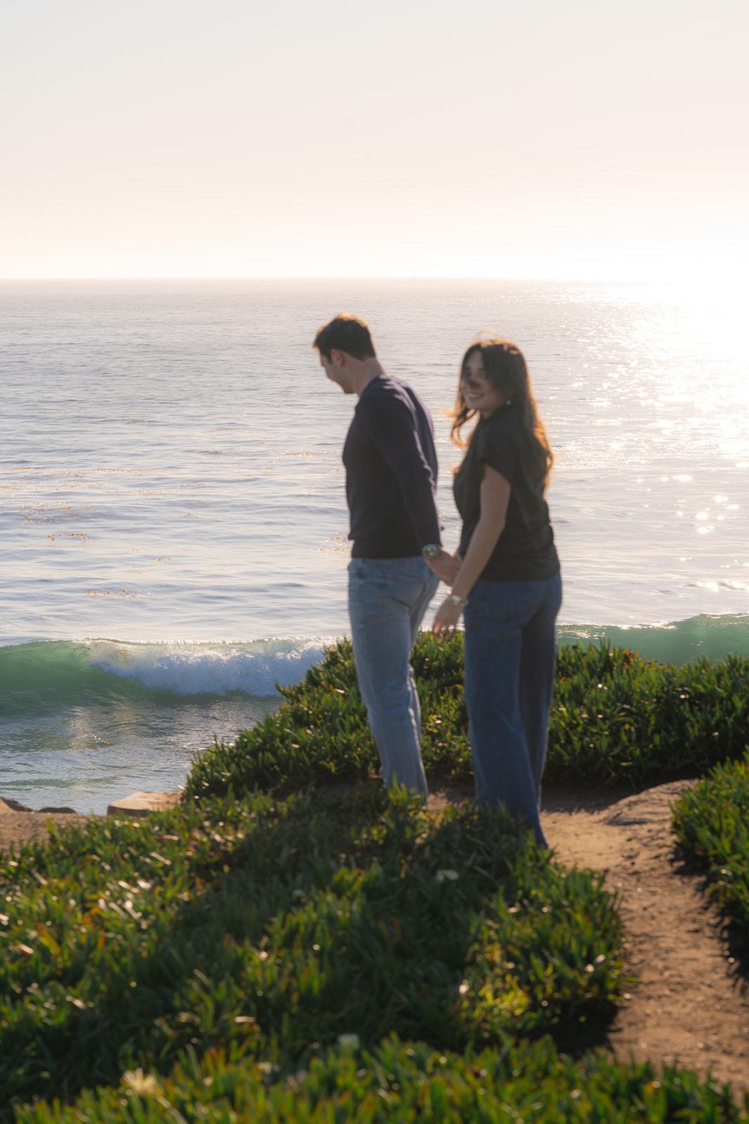 Couple overlooking the sparkling ocean at sunset from a scenic cliffside in Aptos, California.