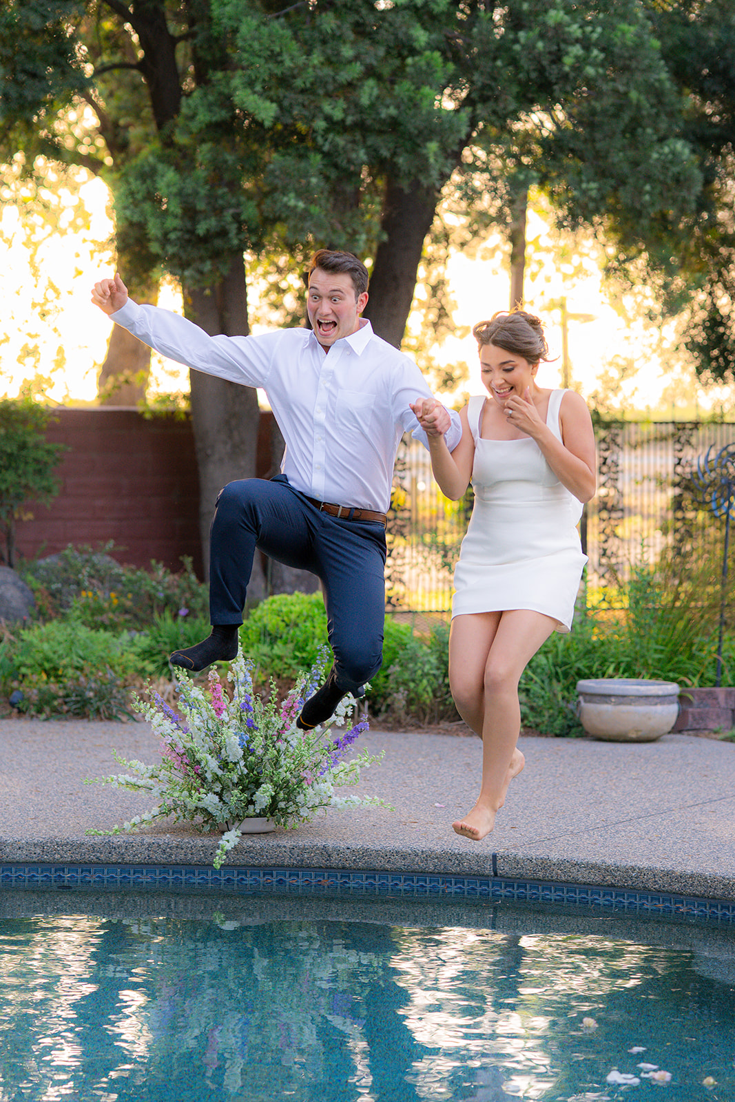Bride and groom jumping into a swimming pool together for their wedding exit at Rainbow Oaks Ranch in Sanger, California.