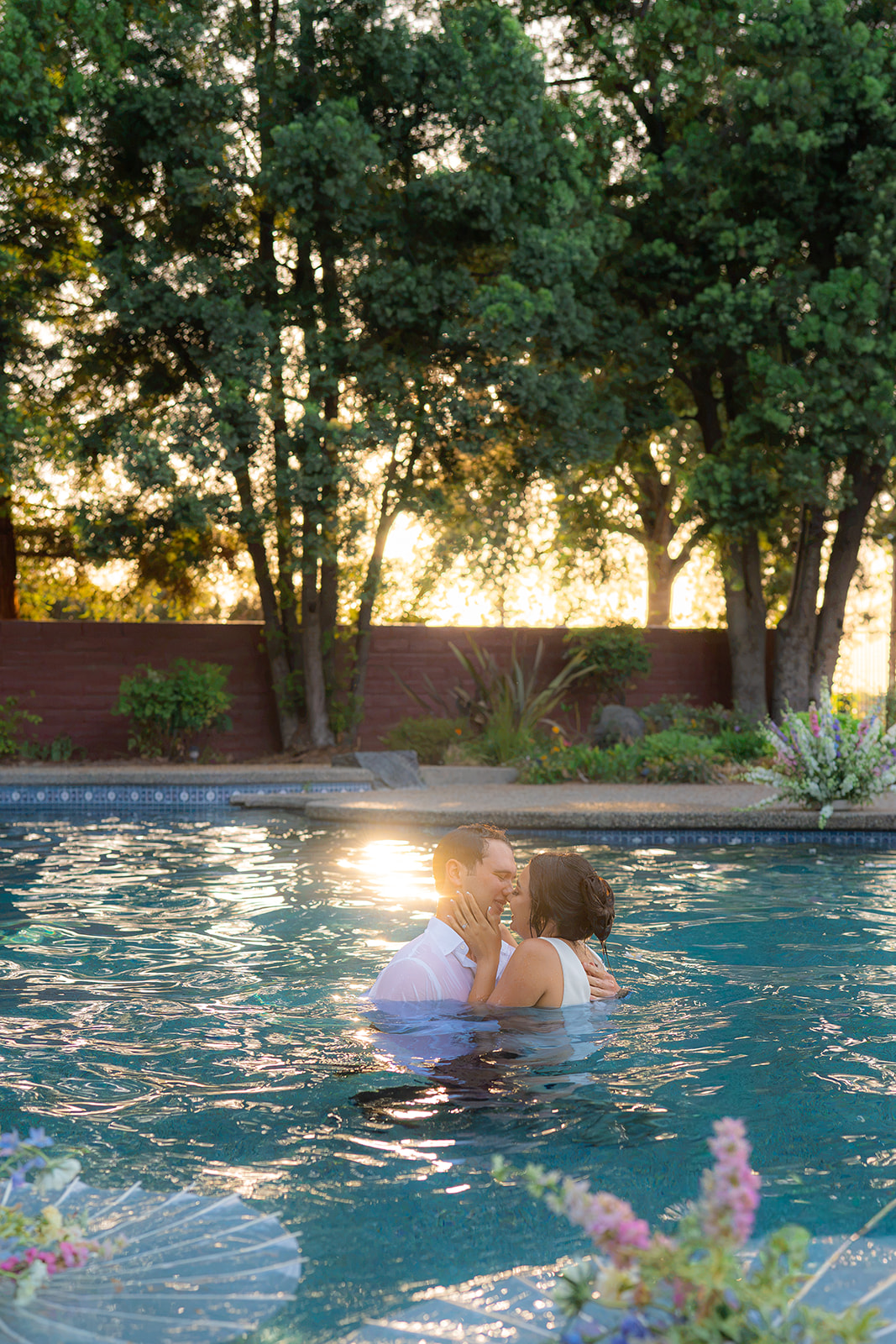 Bride and groom embracing in a swimming pool at sunset at Rainbow Oaks Ranch in Sanger, California.