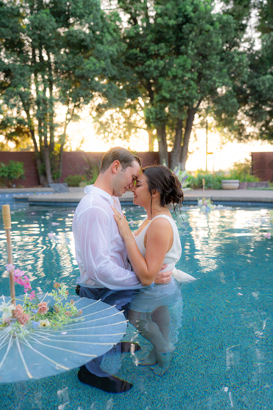 Bride and groom posing together in a swimming pool during their garden wedding at Rainbow Oaks Ranch in Sanger, California.