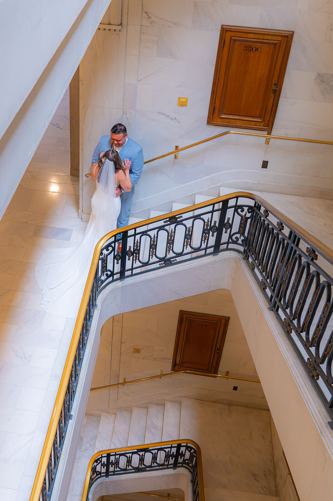Bride and groom posing together in a stairwell at San Francisco City Hall during their wedding.