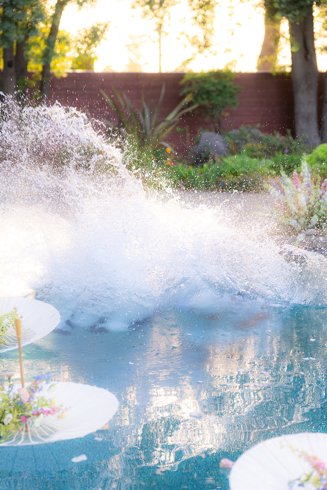 Bride and groom jumping into a swimming pool together at Rainbow Oaks Ranch in Sanger, California.
