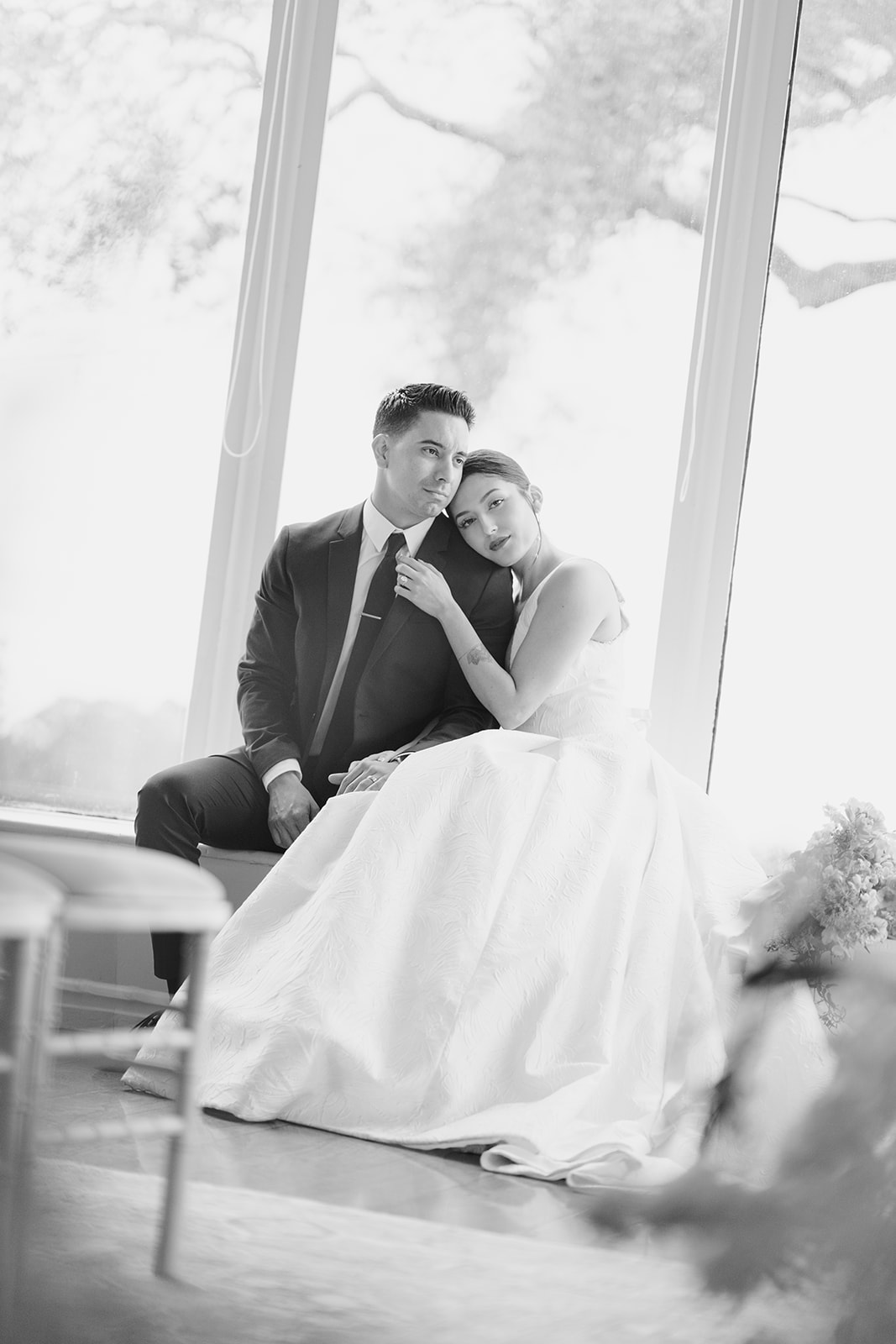 Bride and groom sitting together in a window with soft, serious expressions at Hollins House in Santa Cruz, California.