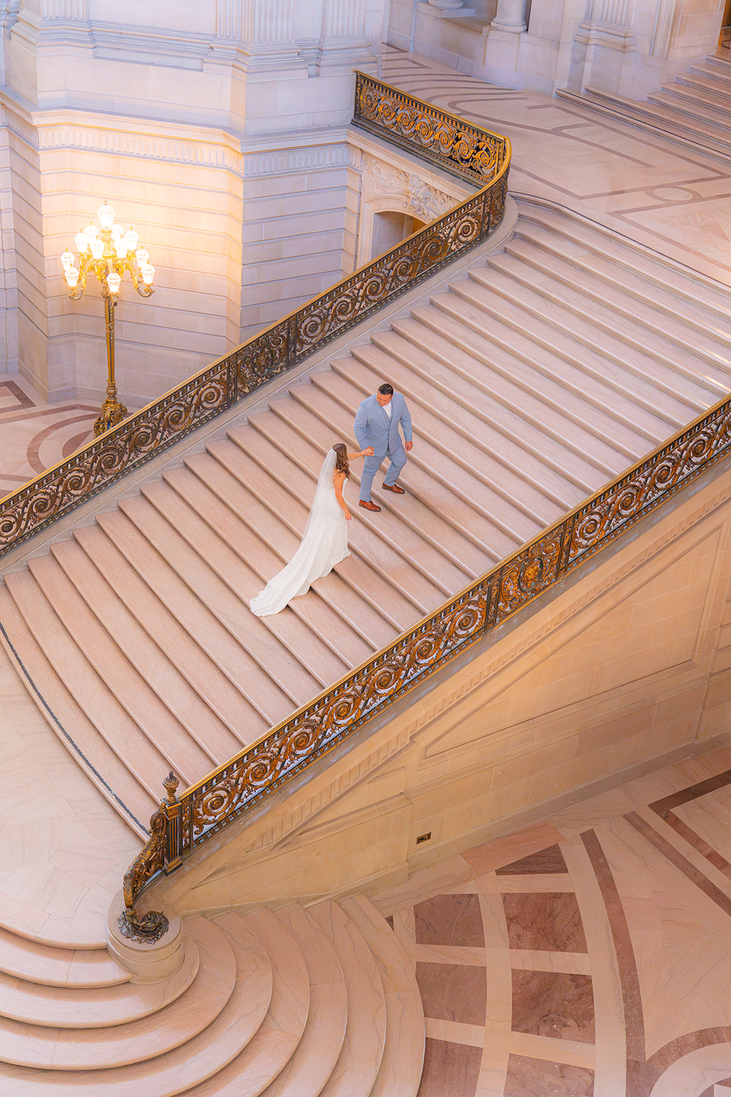 Bride and groom walking up a staircase together during their wedding at San Francisco City Hall.