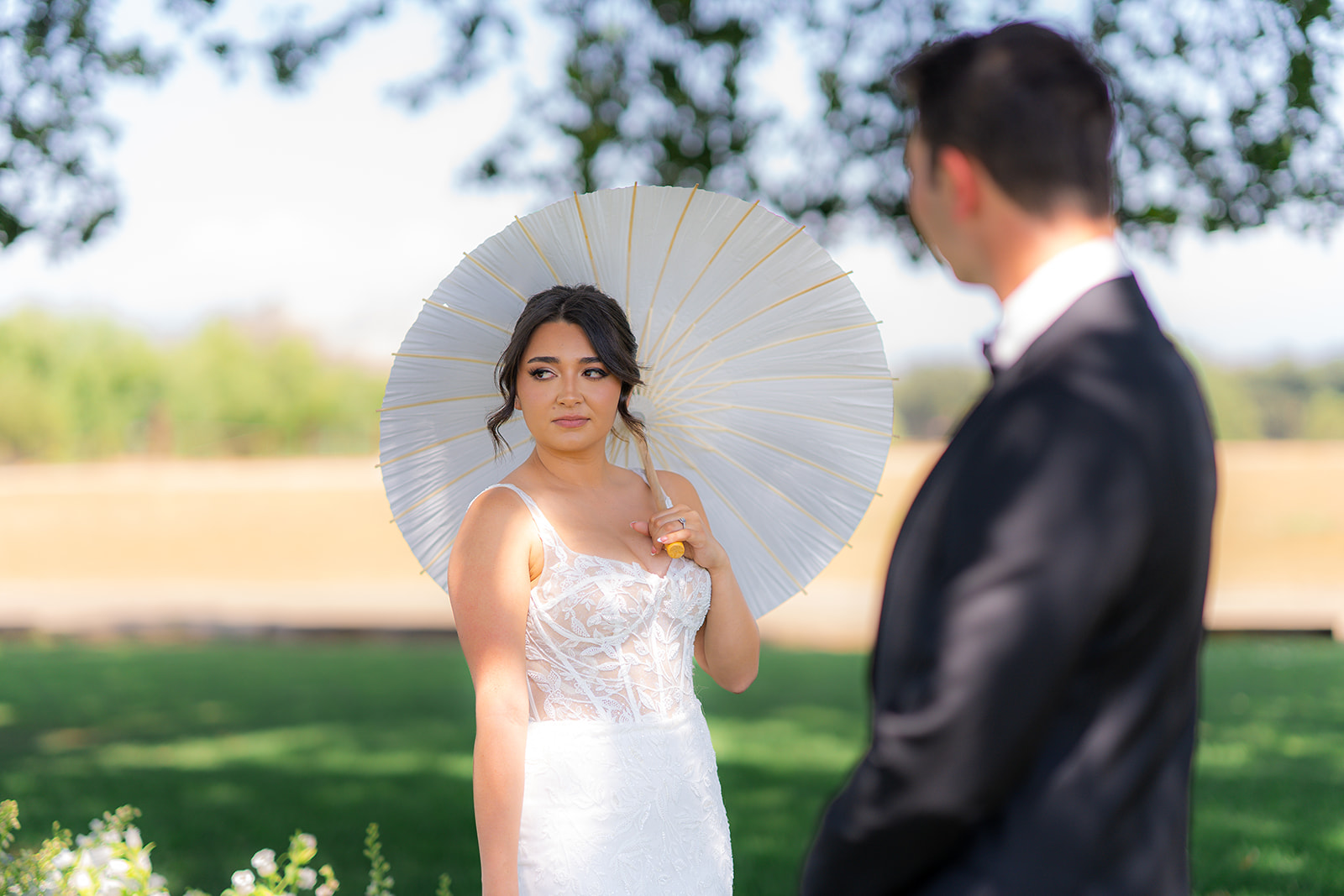 Bride and groom posing together with a parasol umbrella at Rainbow Oaks Ranch in Sanger, California.