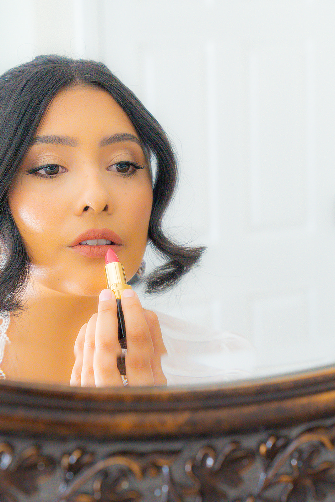 Bride applying lipstick during a bridal portrait session at Olive Hill Estate in Byron, California.
