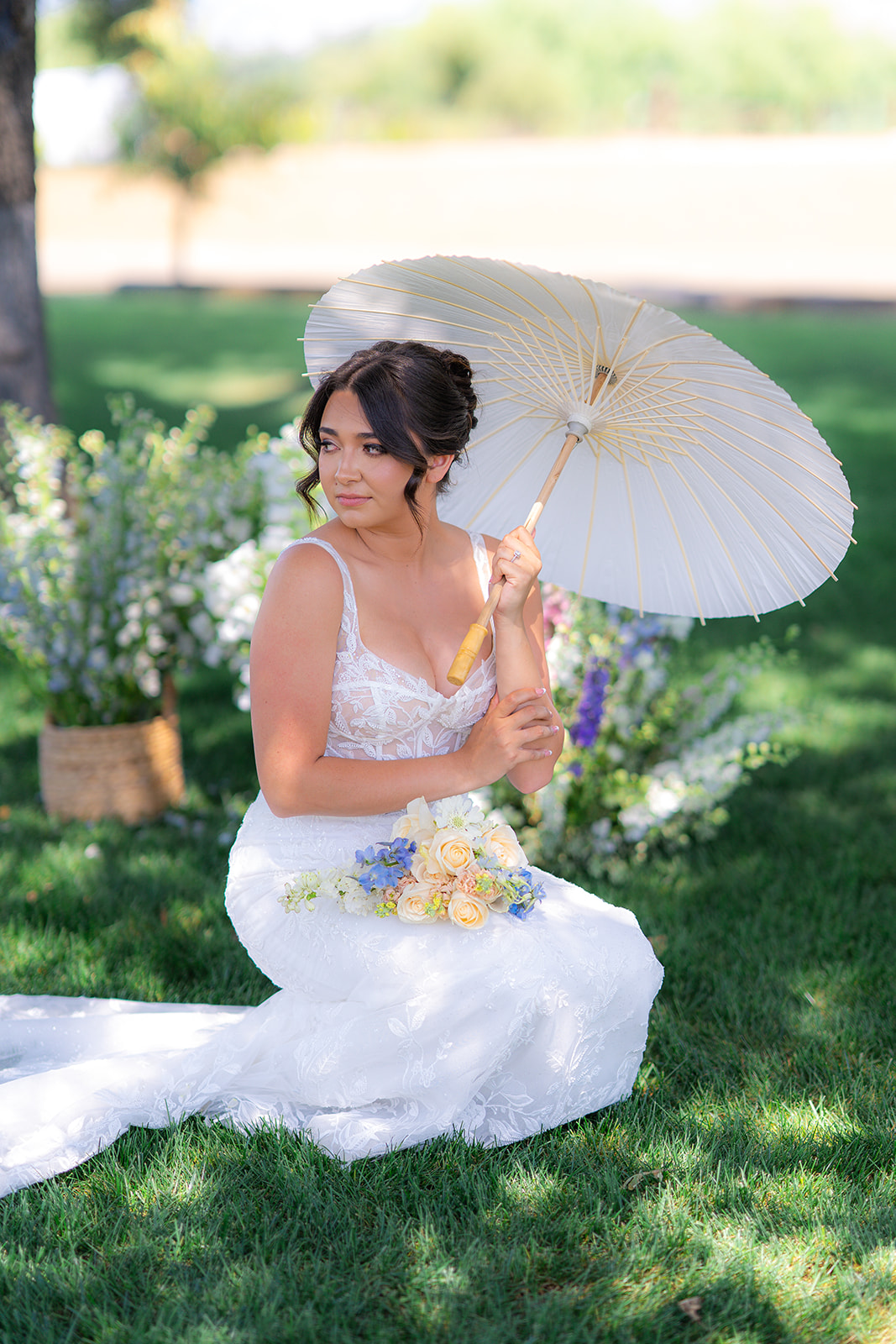 Bride sitting beneath a tree with a parasol at Rainbow Oaks Ranch in Sanger, California.