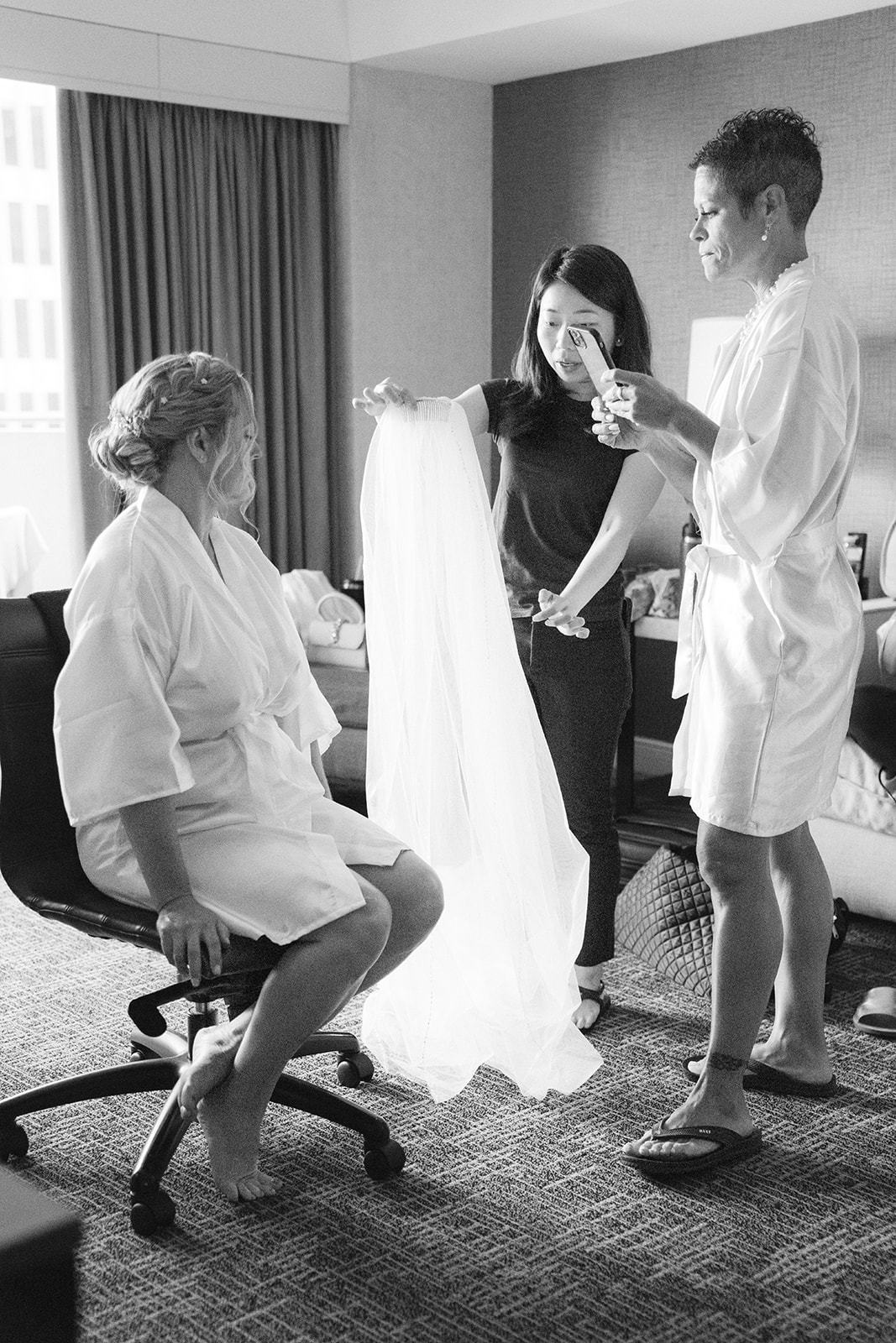 Black and white photo of a bride having her hair styled before her wedding at a San Francisco hotel