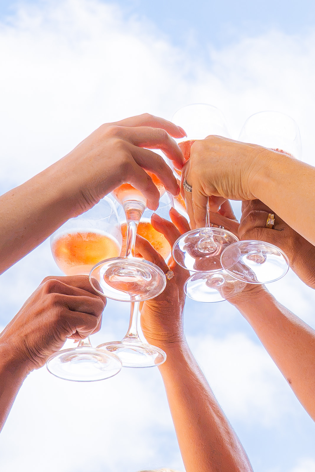 Bridesmaids raising glasses for a wedding toast in San Francisco with clouds reflected in the glasses