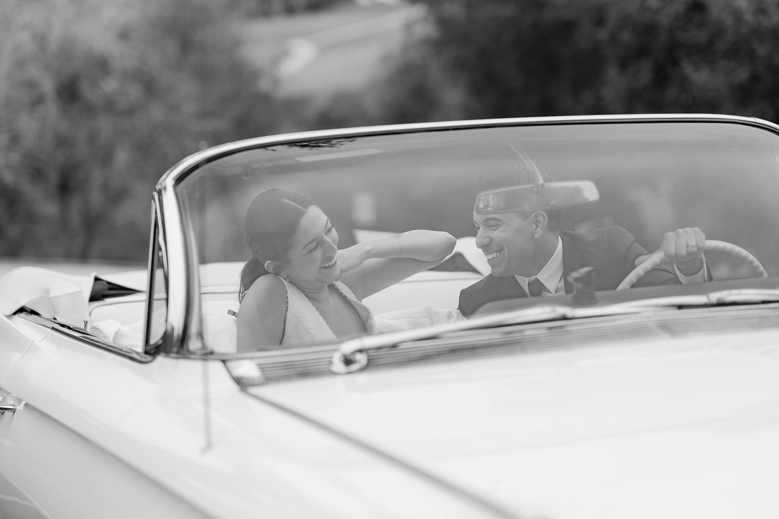 Bride and groom laughing together beside a classic car at Hollins House in Santa Cruz, California.