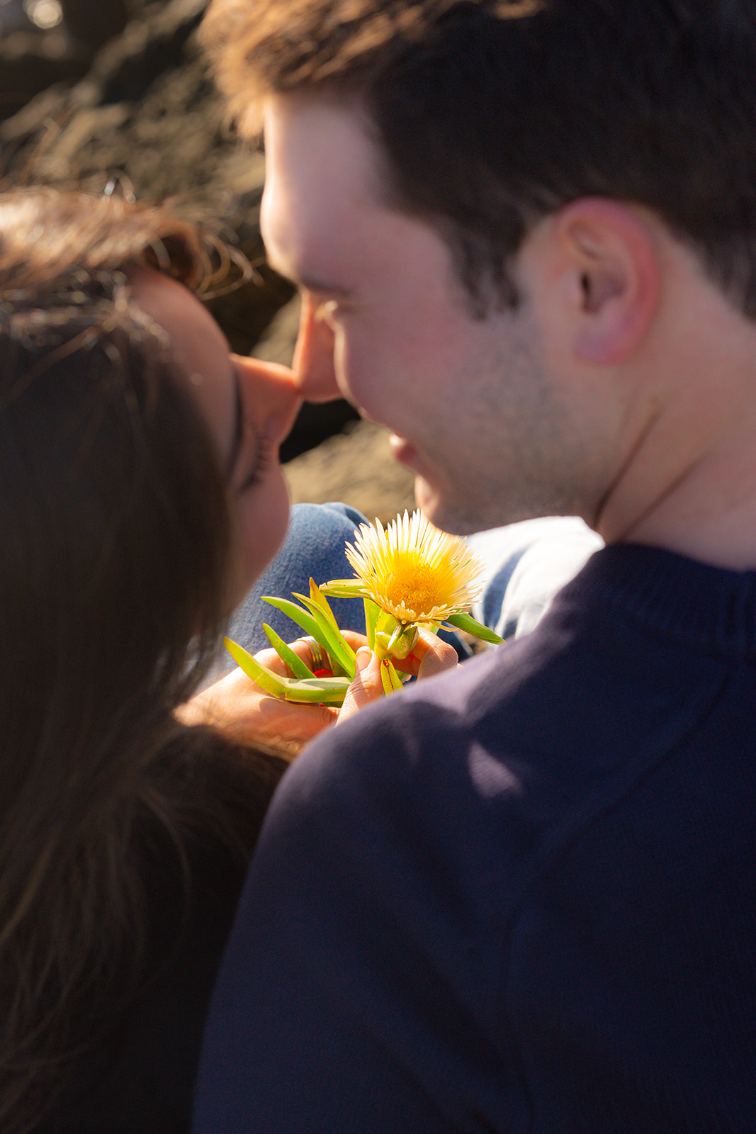 Close-up portrait of a couple with a flower on a scenic cliffside in Santa Cruz.
