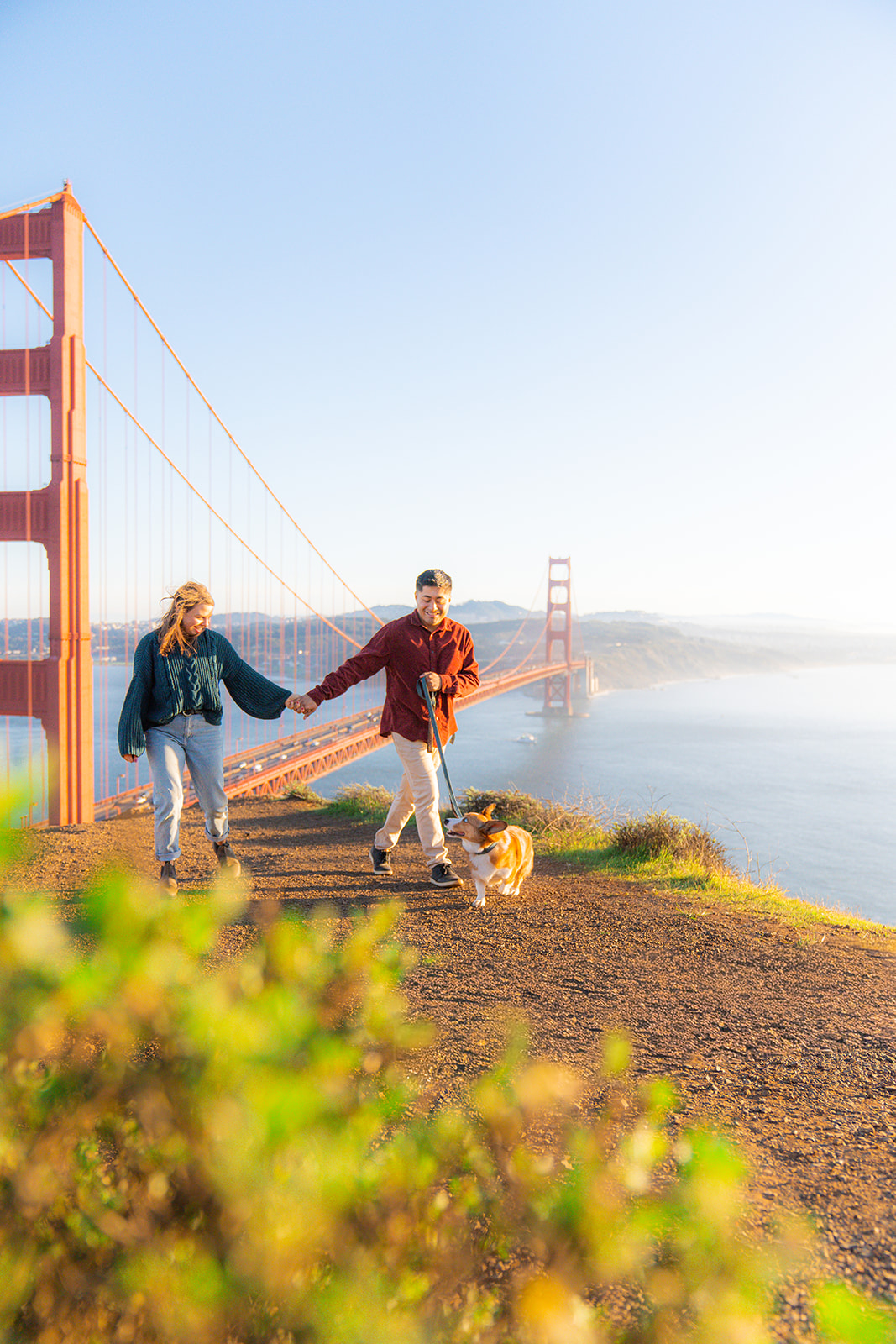 Couple walking with their dog near the Golden Gate Bridge with scenic Bay Area views.