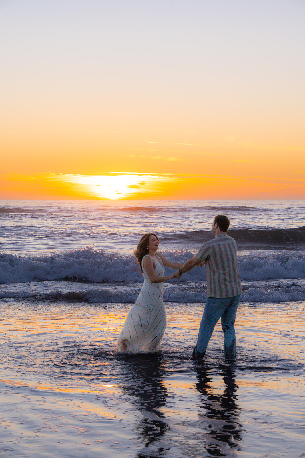 Couple dancing together in the ocean on a beach in Santa Cruz, California.
