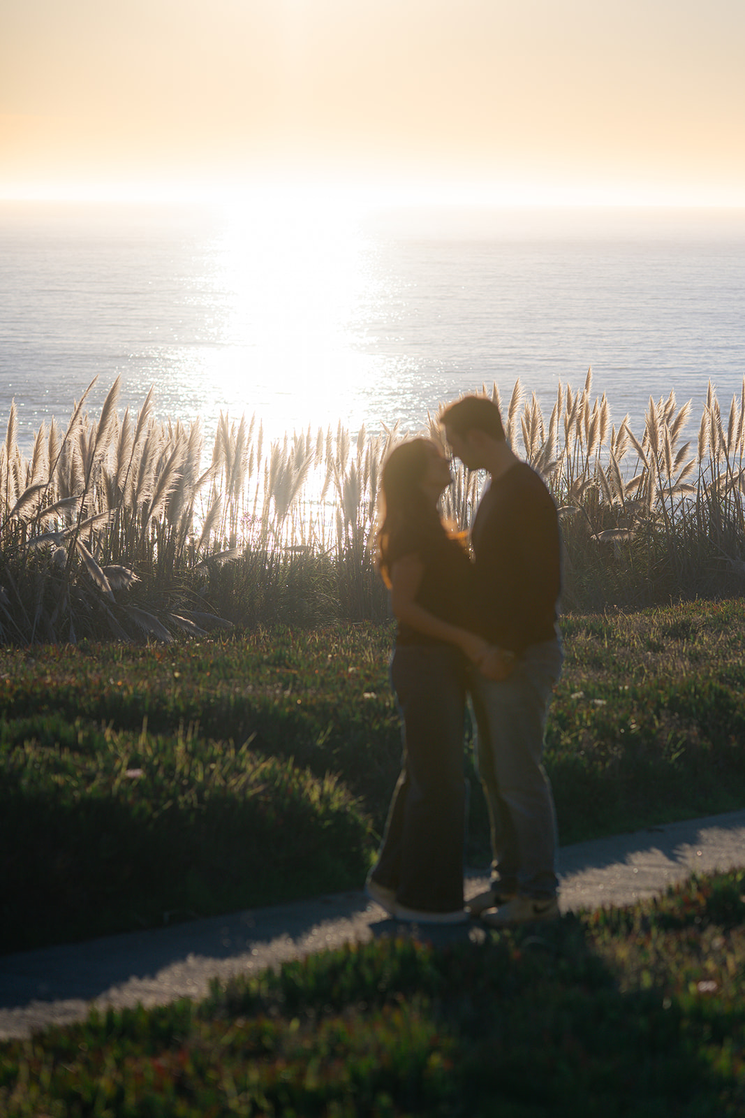 Couple embracing at sunset with the sparkling ocean at Seascape Beach Resort in Aptos, California.