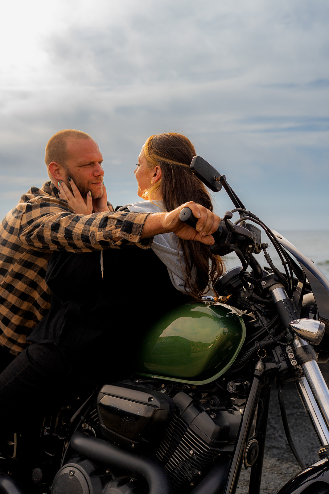 Couple leaning toward each other on a motorcycle in warm sunlight at Pacifica State Beach in California