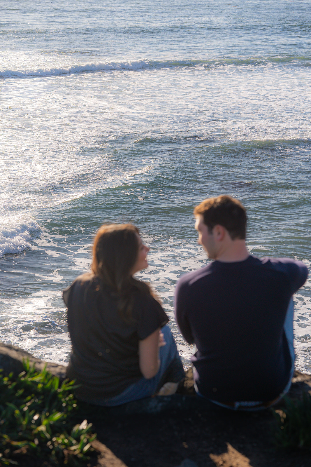 Couple sitting together on a scenic Santa Cruz cliffside overlooking the ocean.