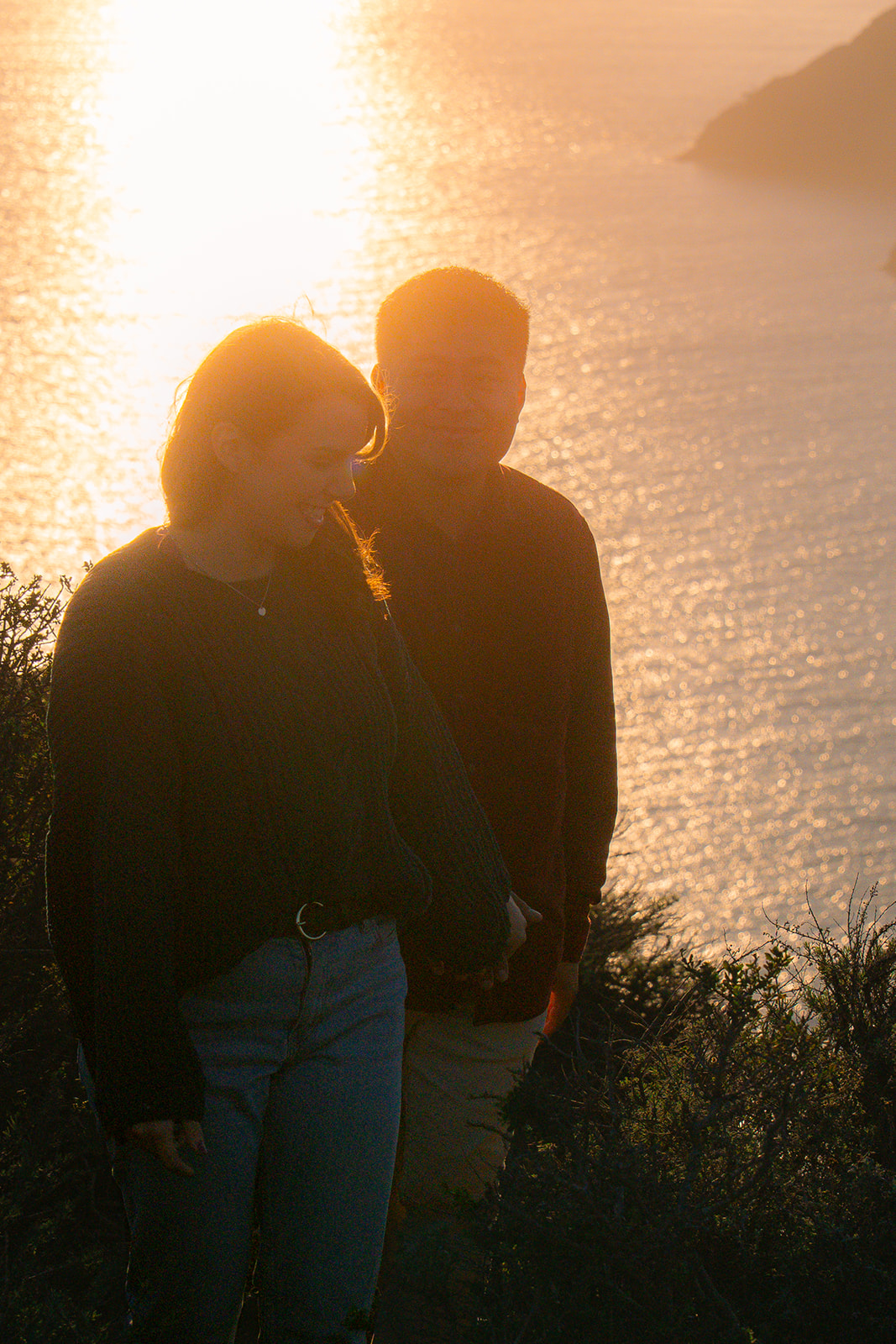 Couple walking at sunset along the cliffside near Battery Spencer in San Francisco.