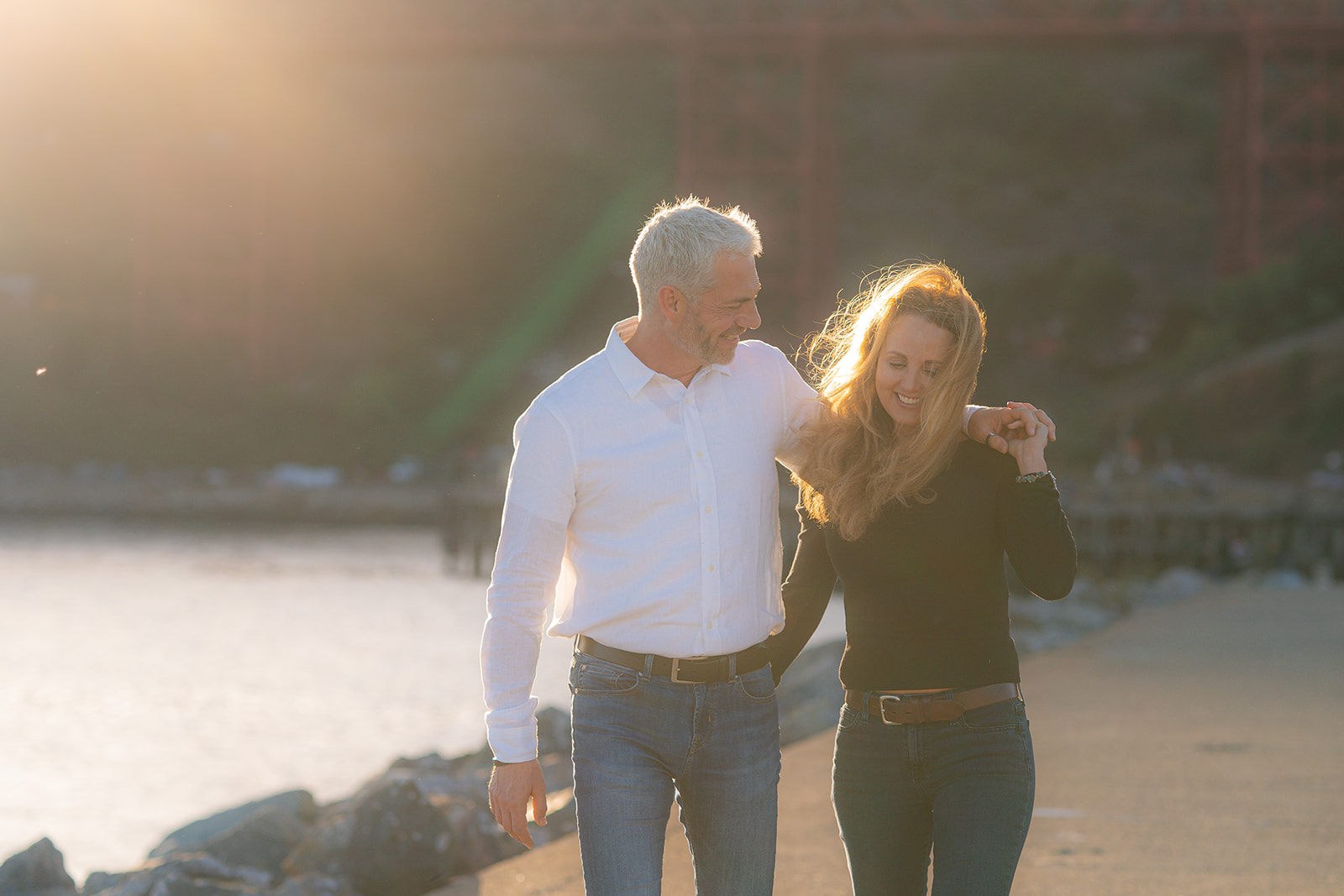 Couple walking by the bay at sunset with the Golden Gate Bridge at Cavallo Point.