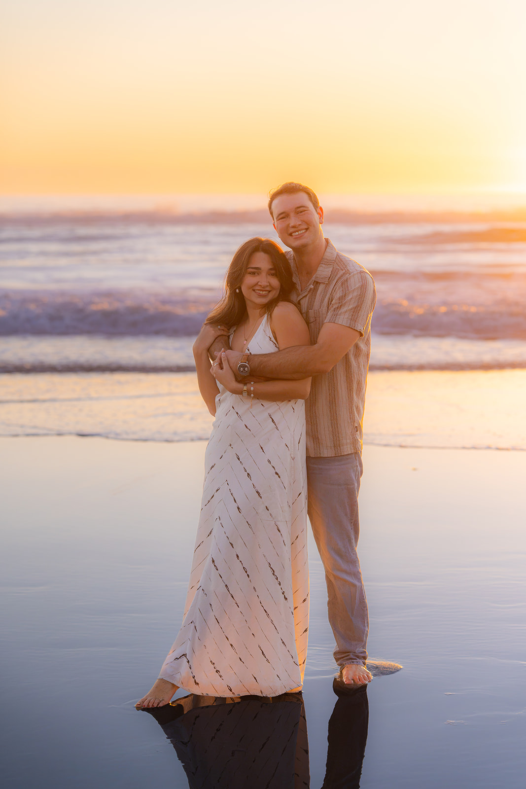 Couple standing barefoot on a Santa Cruz beach during sunset.