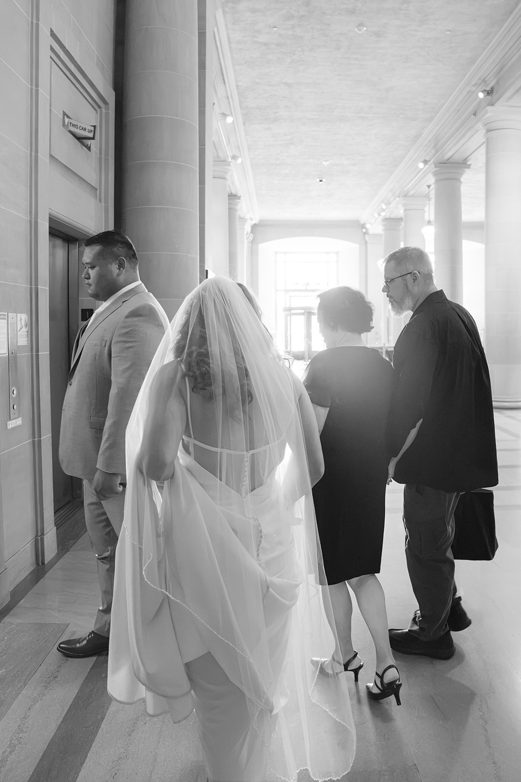 Black-and-white documentary photograph of people walking at a wedding at San Francisco City Hall.