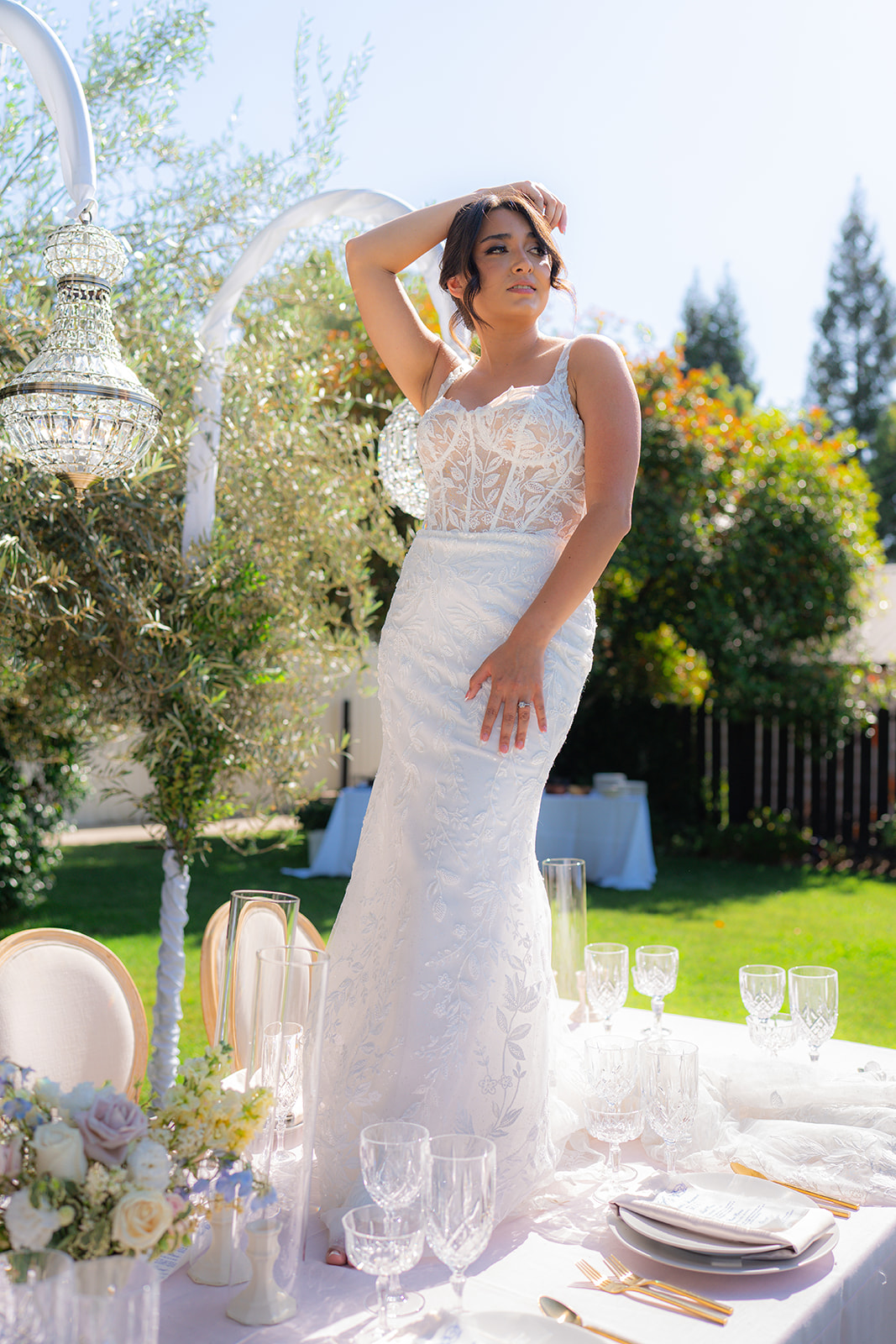 Bride standing on a decorated wedding reception table for an editorial bridal portrait at Rainbow Oaks Ranch in Sanger, California.