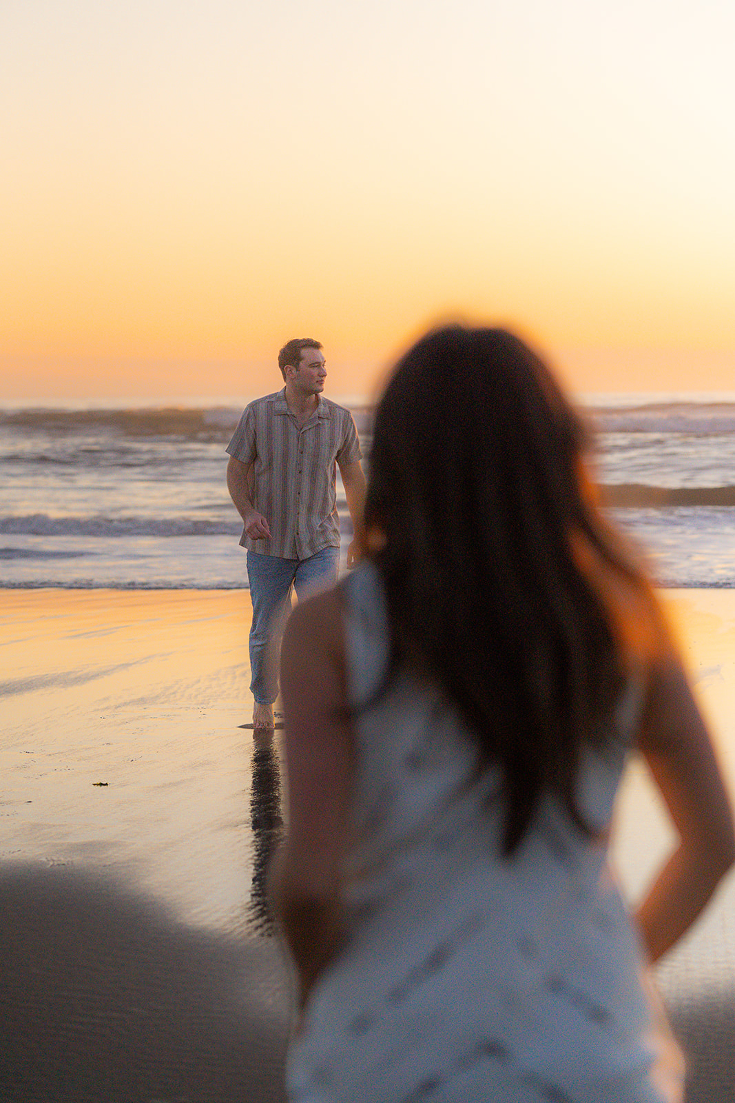 Woman running toward her partner on the beach during an editorial-style couples photo session.