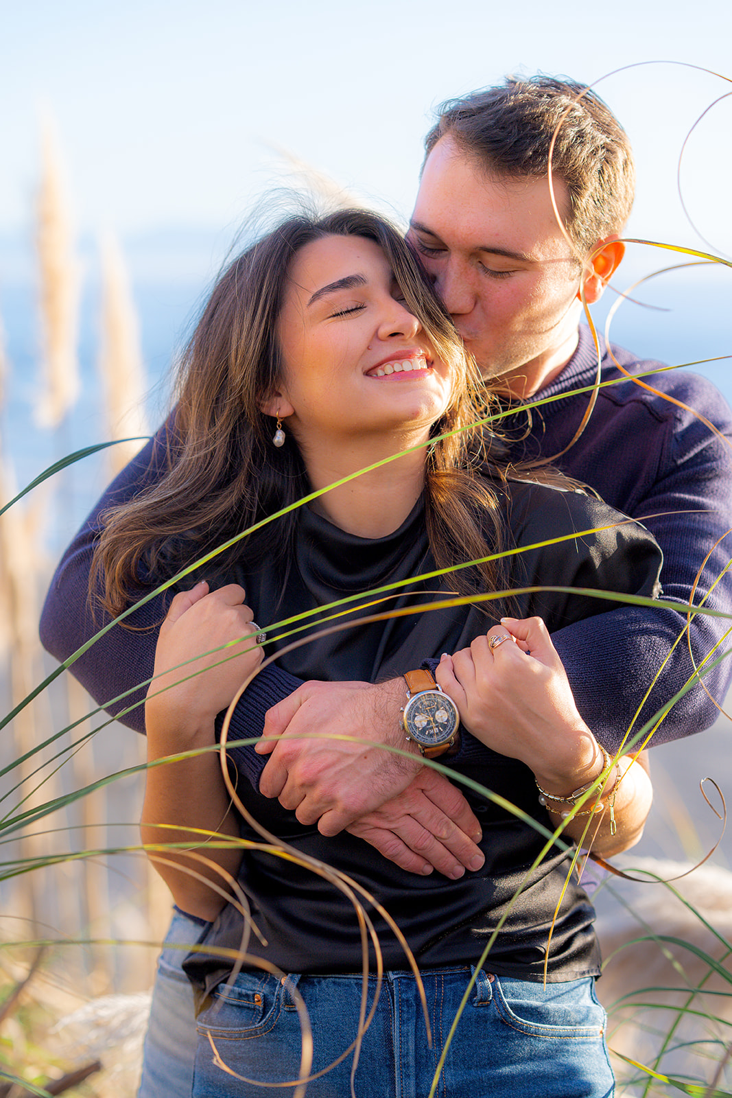 Couple standing in tall coastal grass near the beach in Santa Cruz.