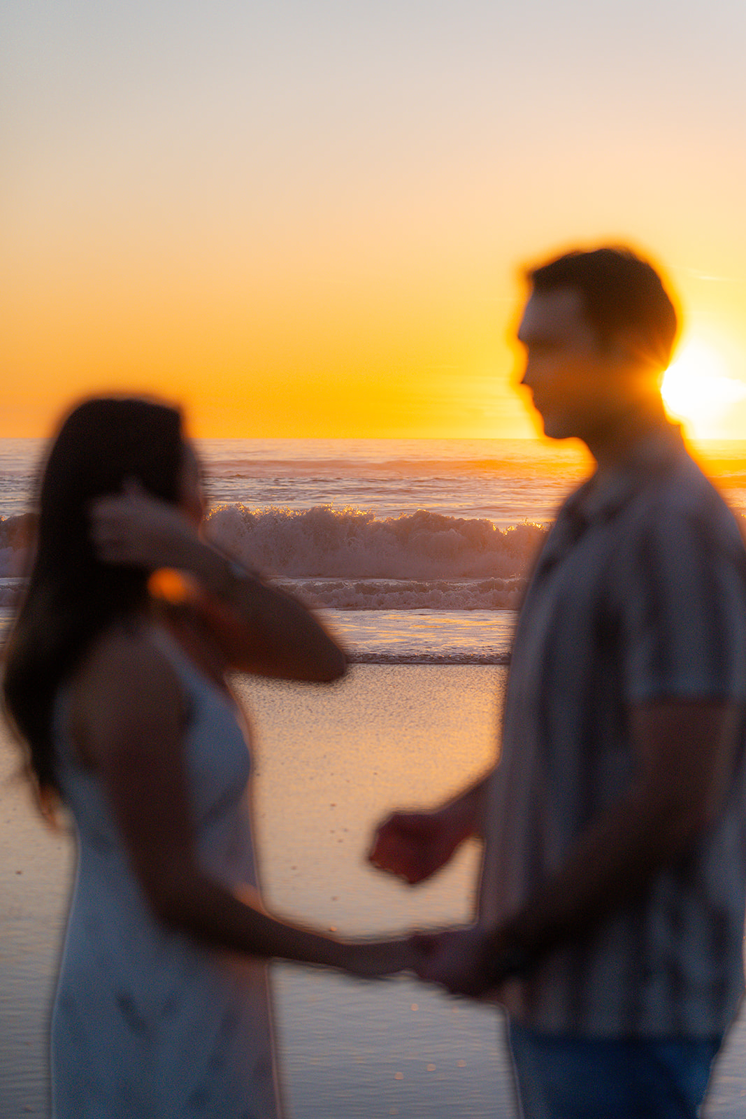 Couple running together along the beach in Santa Cruz during a playful couples session.