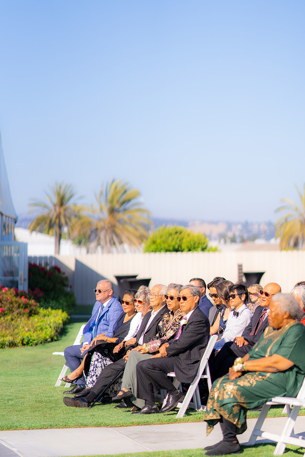 Wedding guests attending an outdoor ceremony on a sunny day at Fairview Metropolitan in Oakland, California.