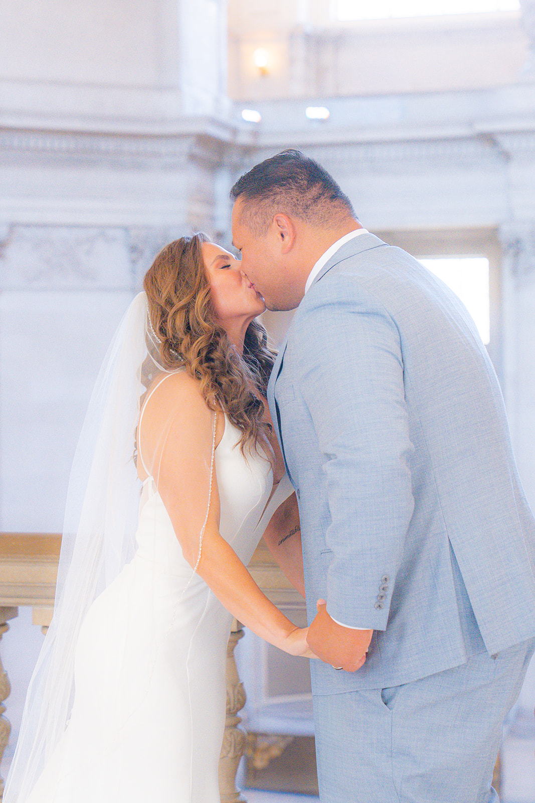 Bride and groom sharing their first kiss as husband and wife during their wedding ceremony at San Francisco City Hall.