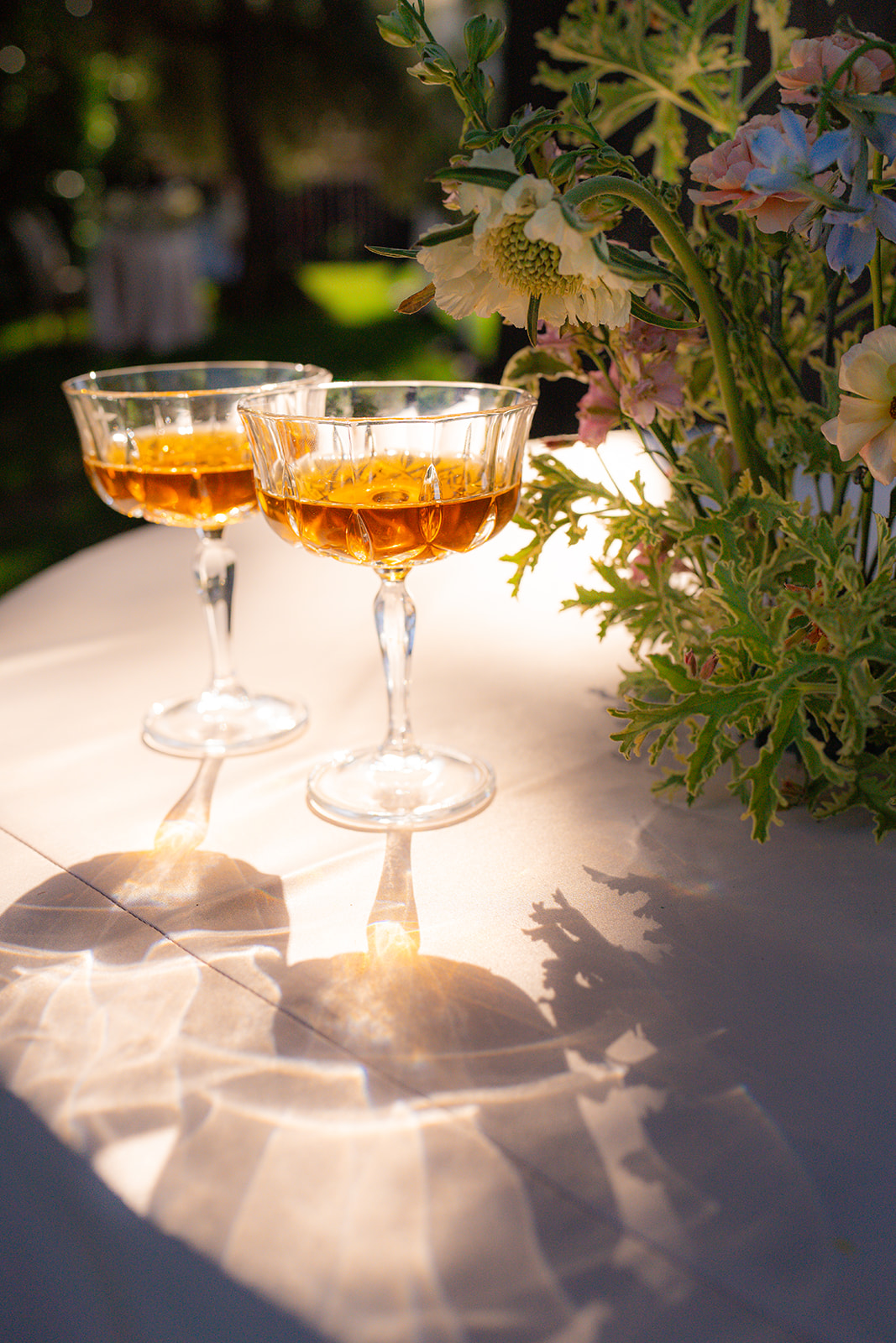 Glasses with flowers arranged as part of the garden wedding décor at Rainbow Oaks Ranch in Sanger, California.