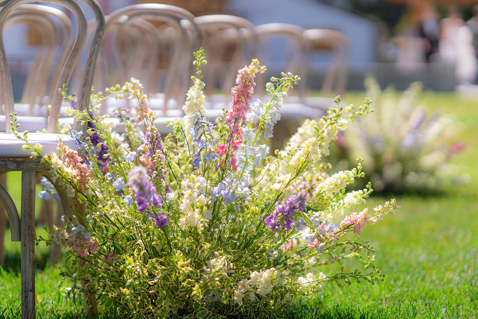 Floral arrangements decorating the aisle of an outdoor garden wedding ceremony at Rainbow Oaks Ranch in Sanger, California.
