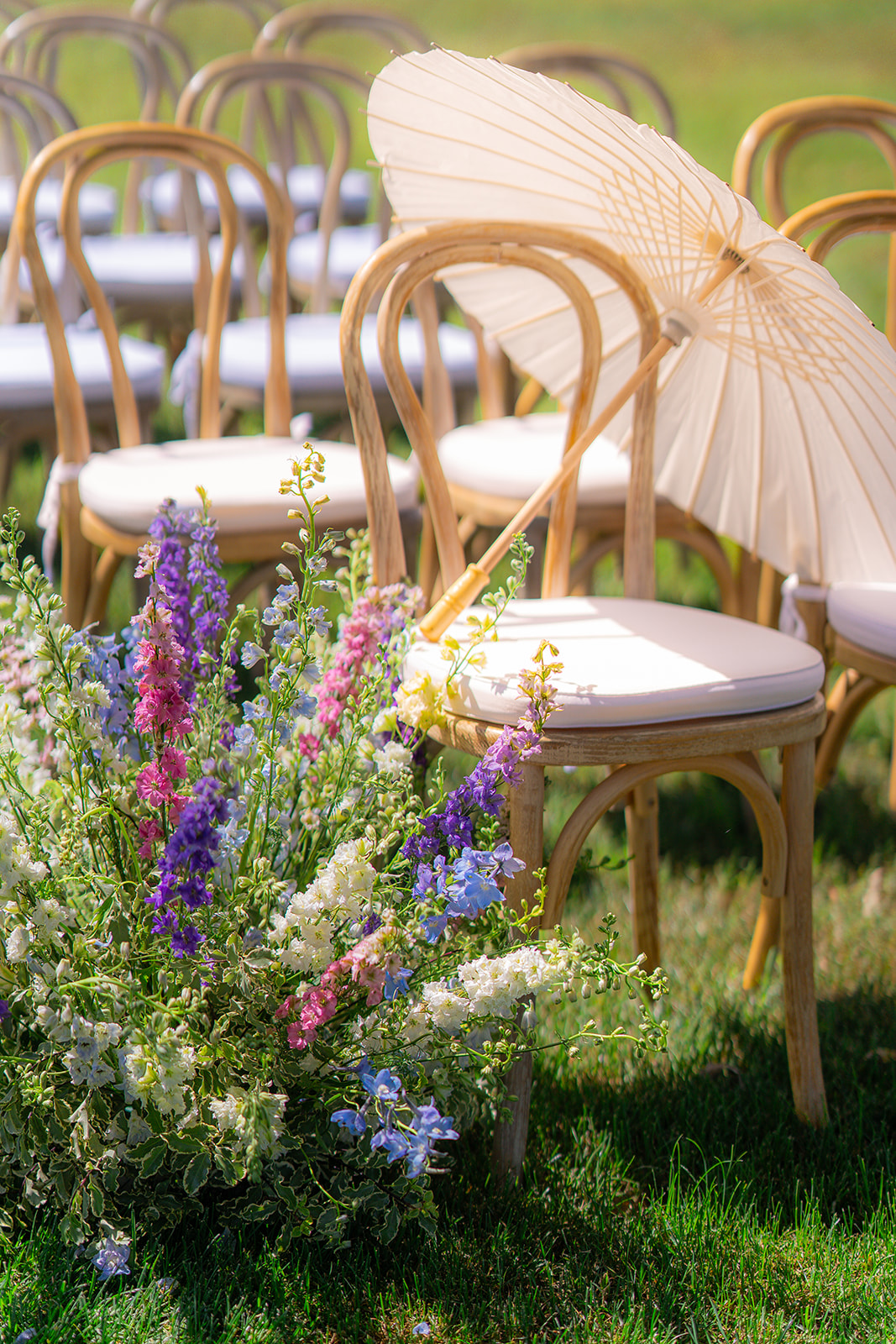 Outdoor garden wedding ceremony setup with chairs, parasol umbrellas, and floral arrangements at Rainbow Oaks Ranch in Sanger, California.