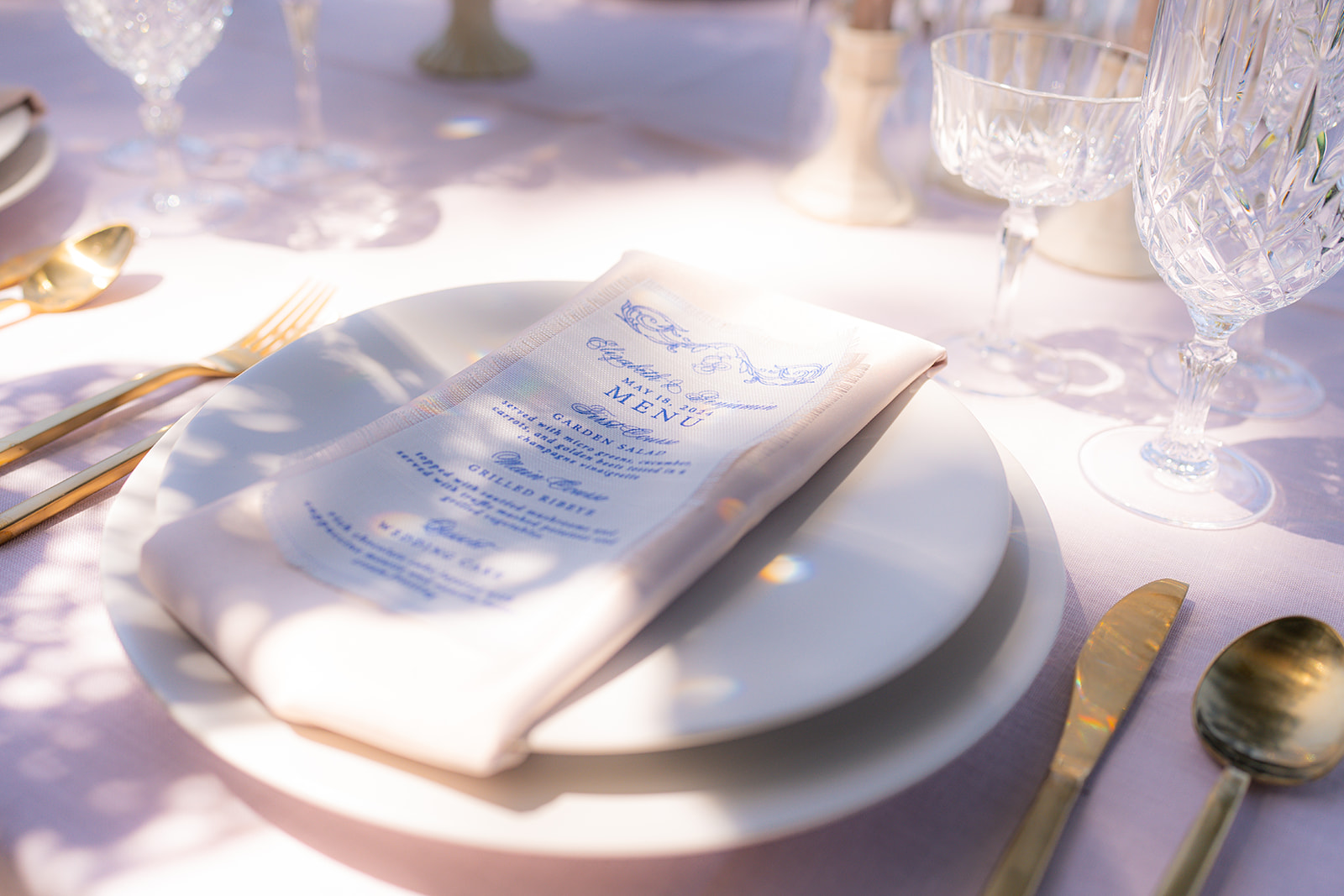 Wedding place setting with a linen napkin and menu, accented by natural shadows at Rainbow Oaks Ranch in Sanger, California.