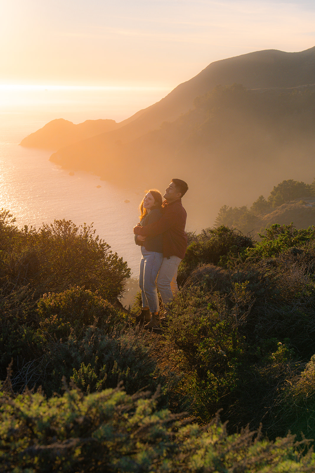 Couple embracing on a cliffside overlooking the ocean during golden hour in San Francisco.