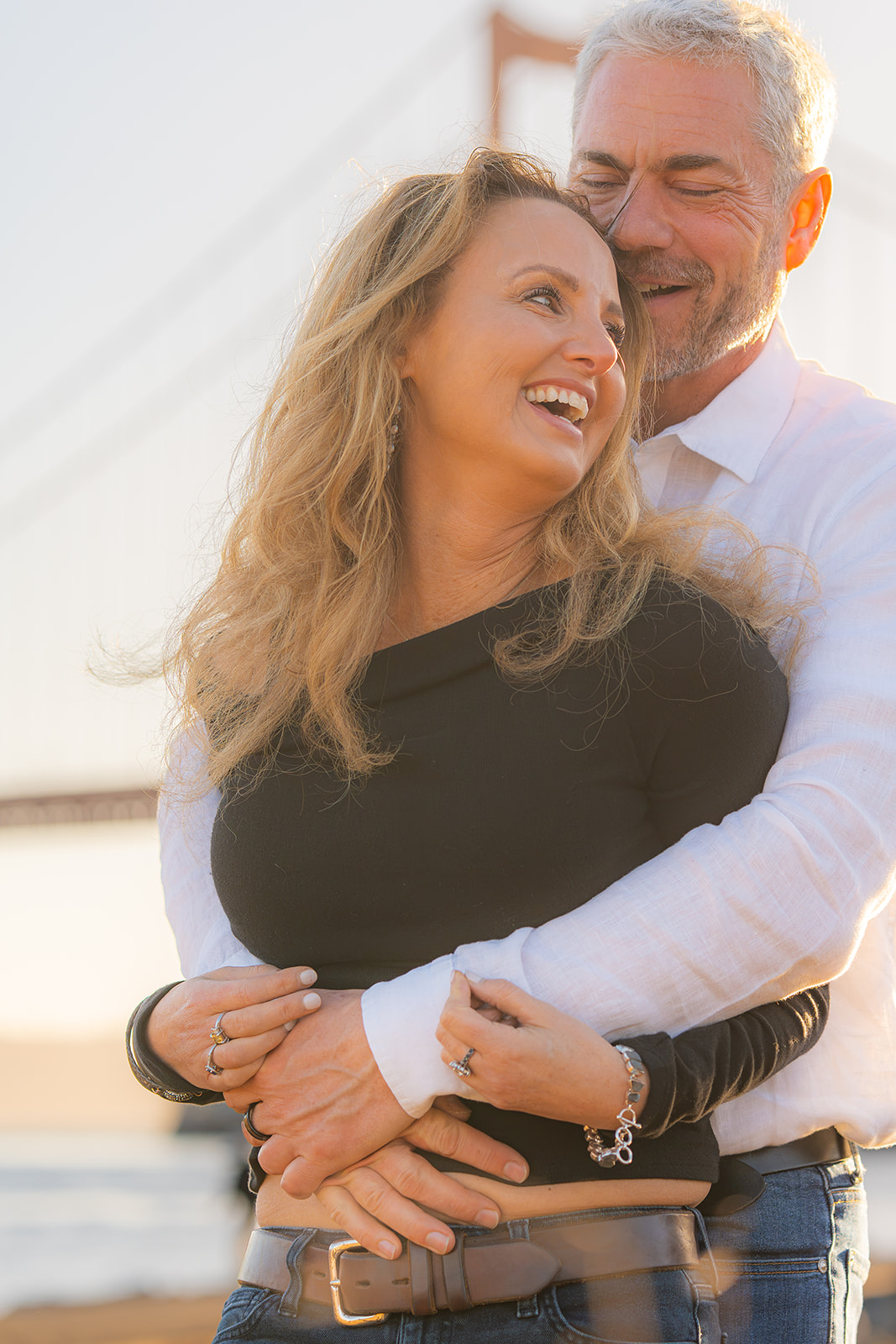 Laughing couple at sunset at Cavallo Point with the Golden Gate Bridge in the background