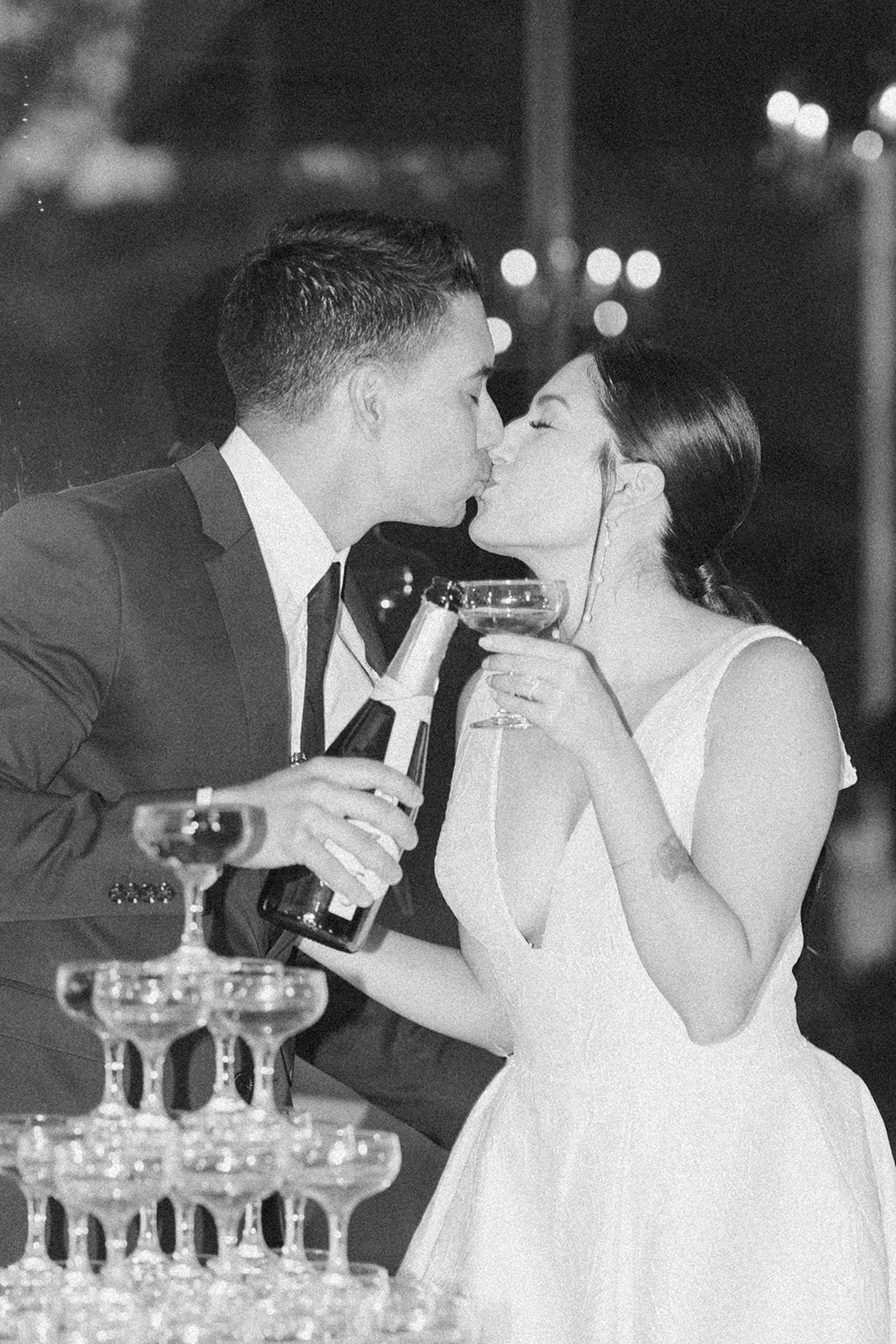 Bride and groom sharing a kiss beside a champagne tower at Hollins House in Santa Cruz, California.
