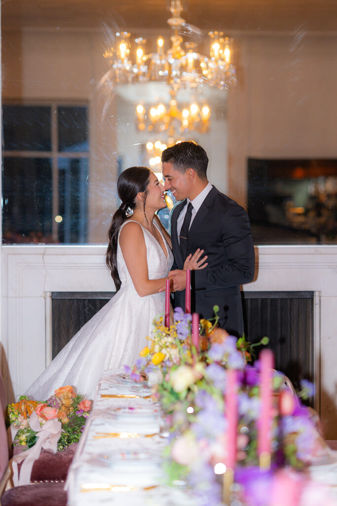 Bride and groom reflected in a mirror with a chandelier at Hollins House in Santa Cruz, California.