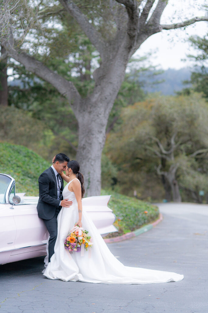 Bride and groom posing beside a classic car at Hollins House in Santa Cruz, California.