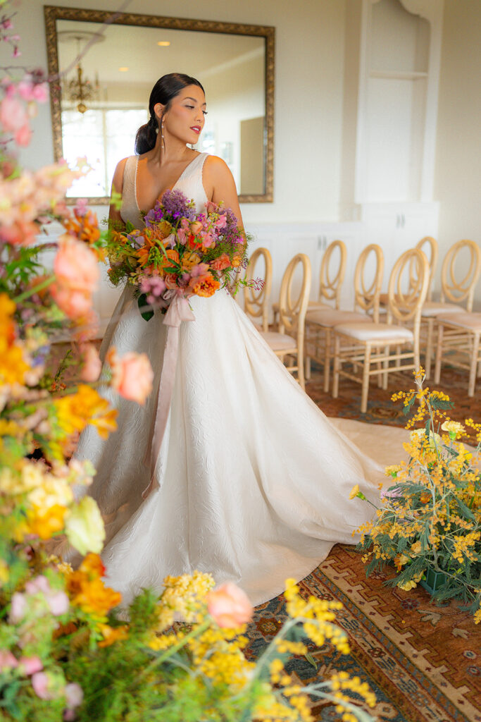 Bride posing with floral arrangements at Hollins House in Santa Cruz, California.