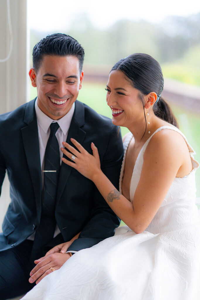 A couple laughing together in their wedding attire at Hollins House in Santa Cruz, California.