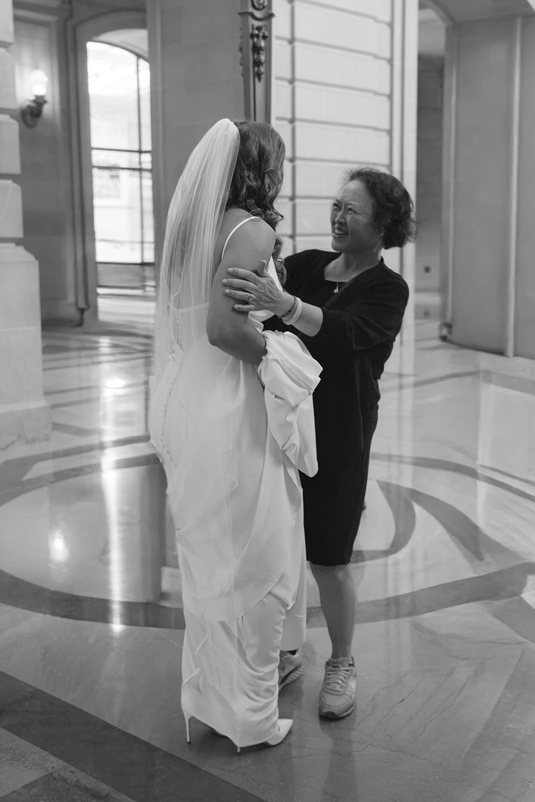 Bride meeting the mother of the groom downstairs at San Francisco City Hall during a wedding.