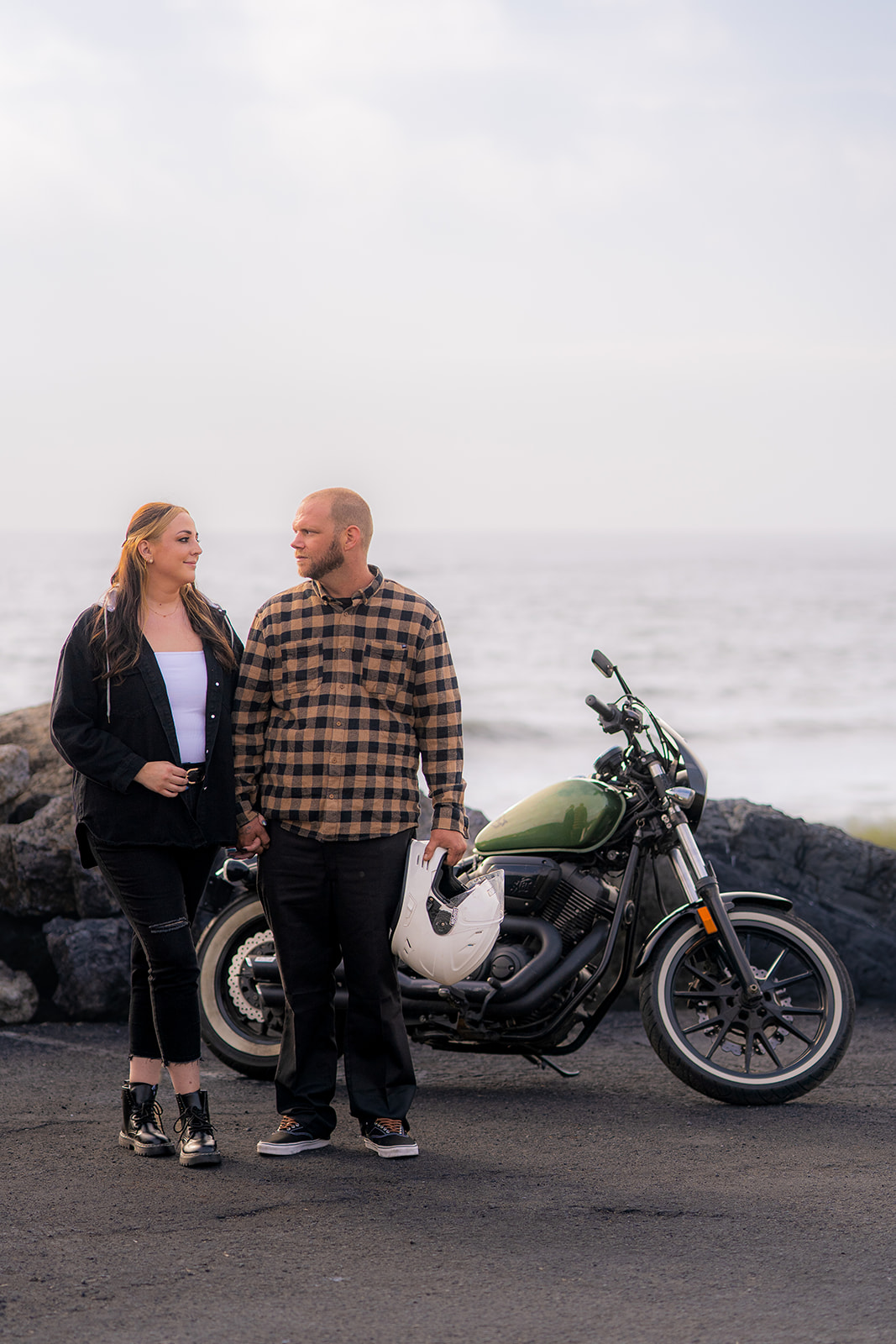 Couple standing together with their motorcycle beside Pacifica State Beach on the California coast