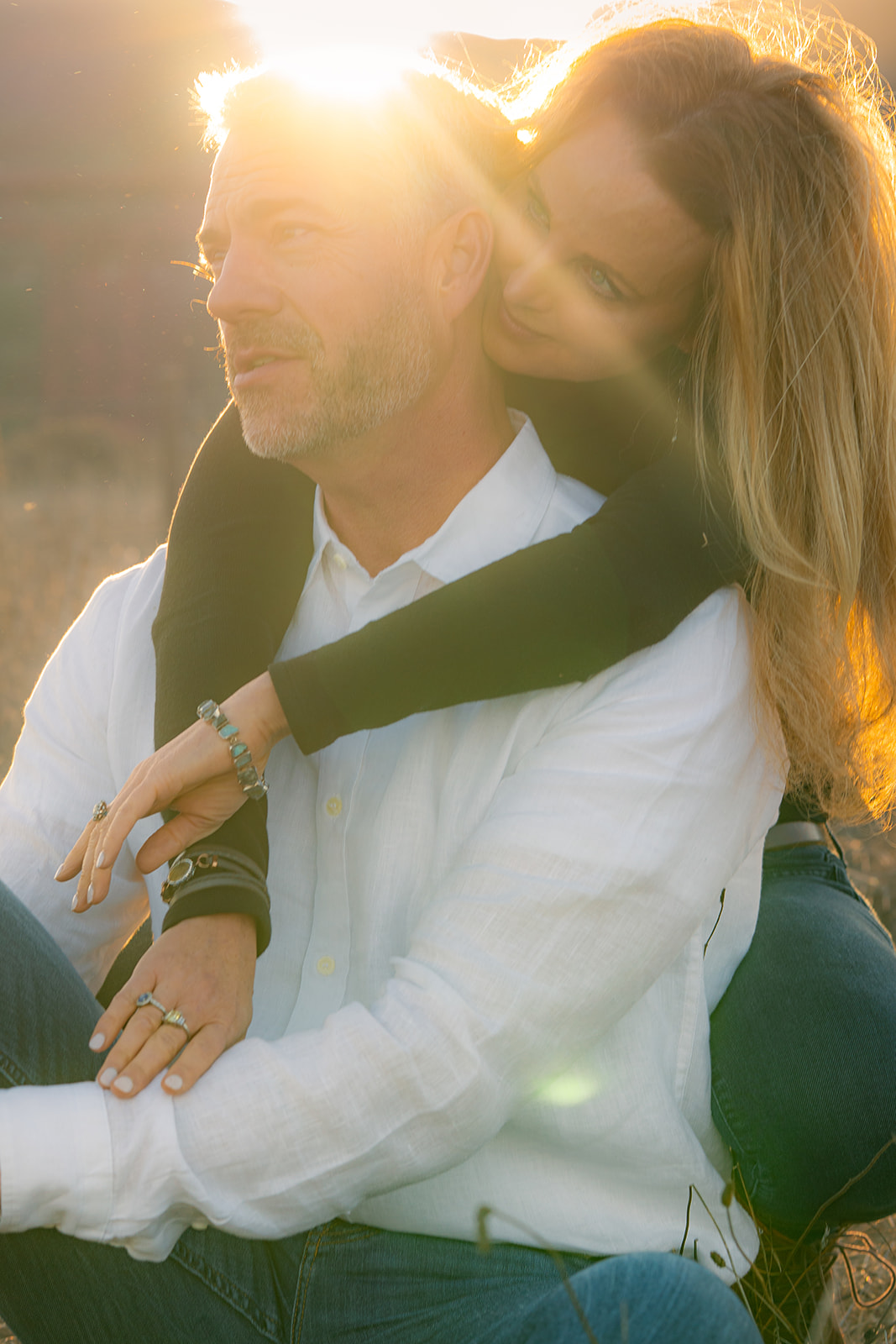 Playful couple sitting together at sunset at Cavallo Point with the Golden Gate Bridge in the background