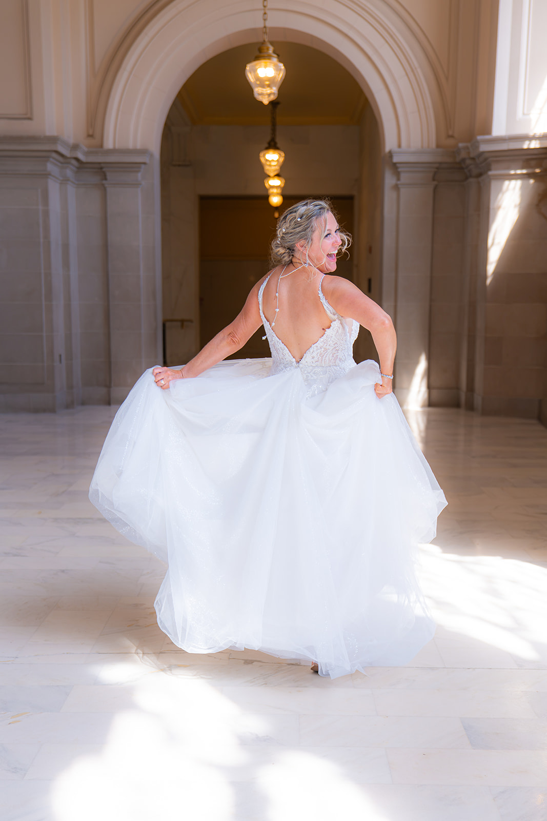Bride running through a hallway inside San Francisco City Hall on her wedding day