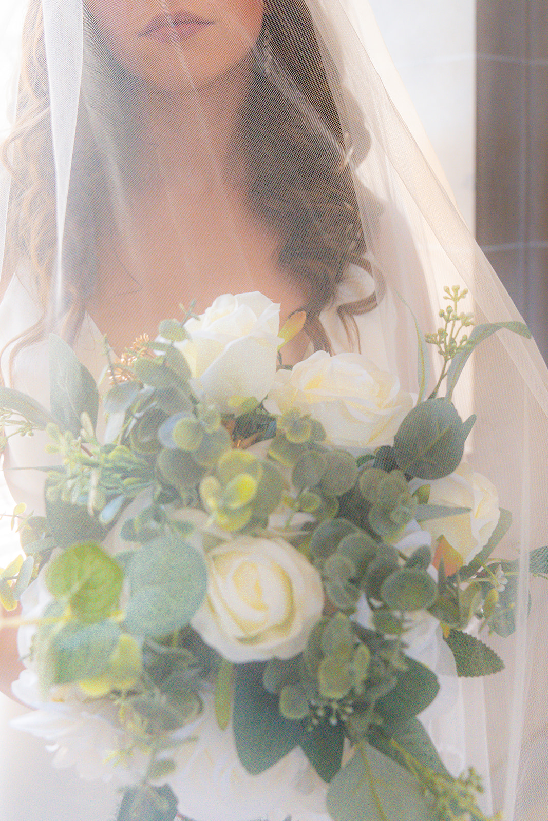 Bride holding flowers beneath her wedding veil at San Francisco City Hall.