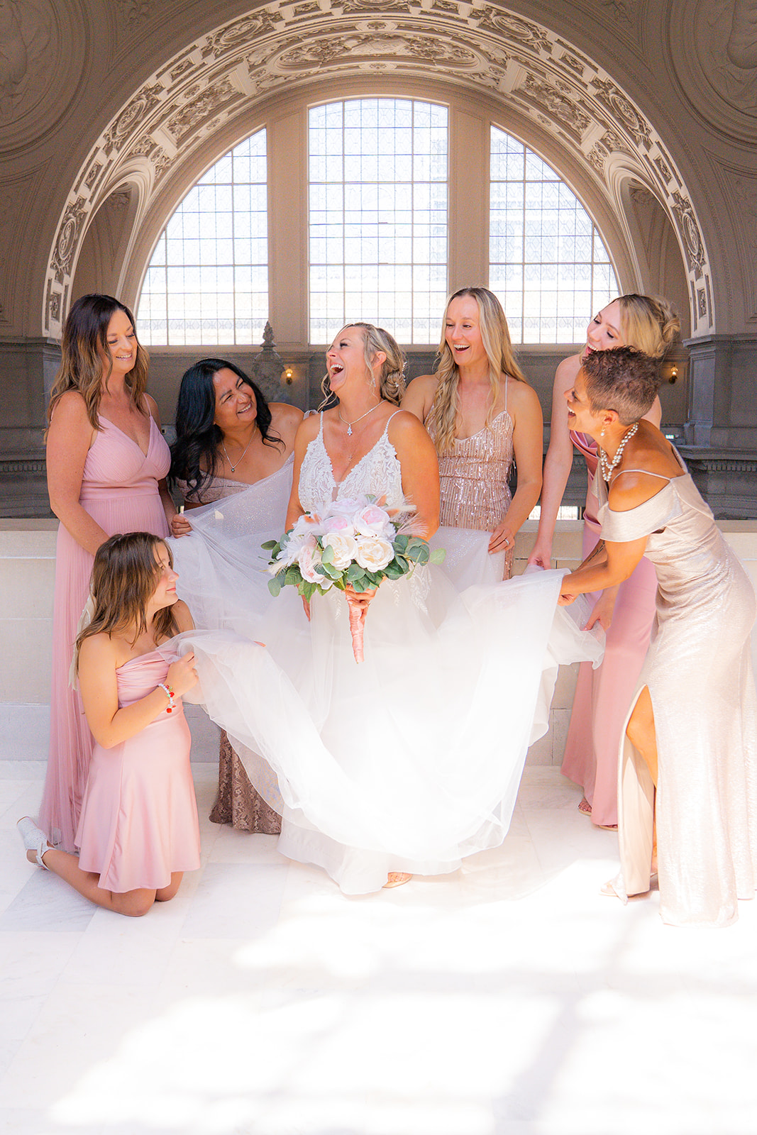 Bridesmaids fluffing the bride’s wedding dress inside San Francisco City Hall