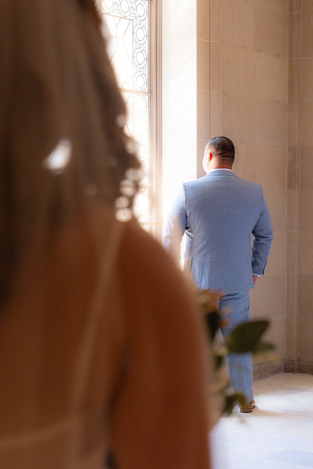 Over-the-shoulder view of the bride during a wedding first look on the second floor of San Francisco City Hall.